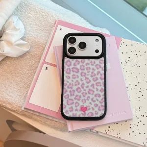 Gros plan d'une coque iPhone à motif léopard rose rétro sur des carnets pastel