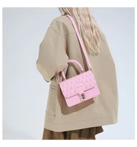 Primer plano de un pequeño bolso cuadrado rosa bordado llevado como bandolera por una modelo