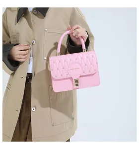 Bolso de mano cuadrado rosa bordado con cierre dorado sostenido por una modelo en gabardina