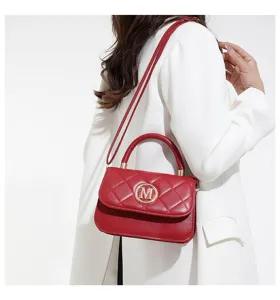 Detailaufnahme einer roten gesteppten Umhängetasche mit goldenem M-Logo, getragen von Model