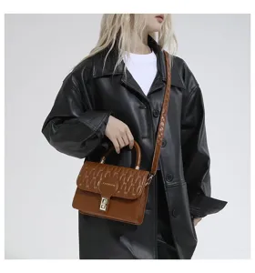 Primer plano de un bolso bandolera bordado marrón sobre chaqueta de cuero negro