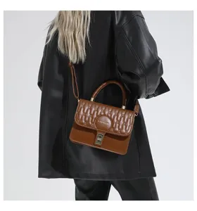 Vista detallada del bolso acolchado marrón llevado por modelo con chaqueta de cuero