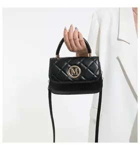 Nahaufnahme einer schwarzen gesteppten Mini-Handtasche mit goldenem M-Logo in der Hand.