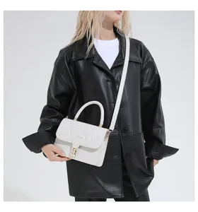Vista detallada de un elegante bolso bordado blanco con cierre dorado y asa superior