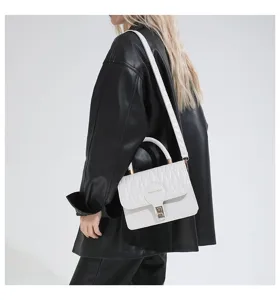 Bolso bandolera bordado blanco con cierre dorado en modelo con chaqueta de cuero
