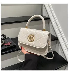 Nahaufnahme einer eleganten cremefarbenen Stepphandtasche mit goldenem M-Logo-Schloss