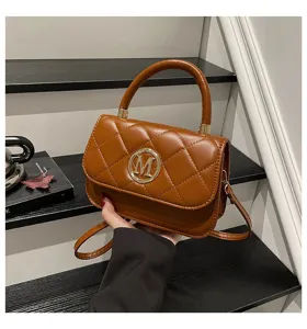 Nahaufnahme einer braunen gesteppten Handtasche mit goldenem M-Logo auf schwarzen Stufen