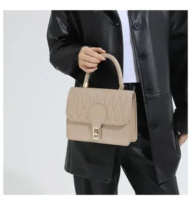 Vista detallada de un bolso bordado beige con un elegante cierre de metal dorado de moda