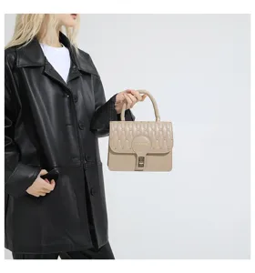 Vista detallada de un elegante bolso bordado beige con un cierre de metal dorado.