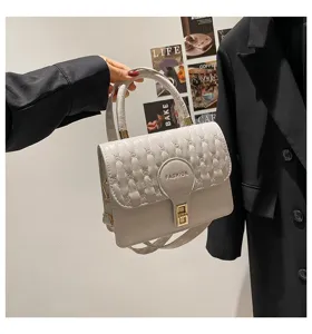 Vista detallada de un elegante bolso cuadrado blanco bordado con cierre metálico y asa
