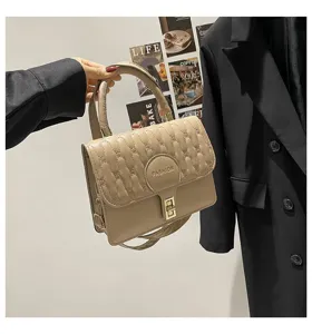 Primer plano detallado de un bolso de mano cuadrado bordado beige con elegante cierre dorado