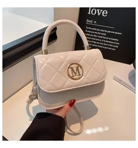 Nahaufnahme einer weißen gesteppten Handtasche mit goldenem 'M'-Logo und Tragegriff.