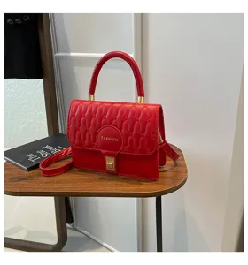 Primer plano de un elegante bolso de mano cuadrado bordado rojo con toques oro.