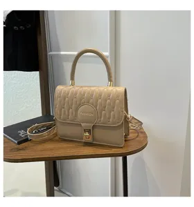 Bolso de mano acolchado beige elegante con asa superior sobre una mesa de madera