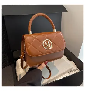 Braune gesteppte Leder-Umhängetasche mit rundem goldenen M-Logo in schwarzer Box