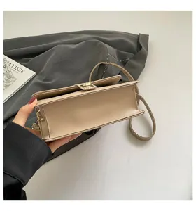 Detalle inferior de un bolso bandolera pequeño bordado albaricoque con broche dorado