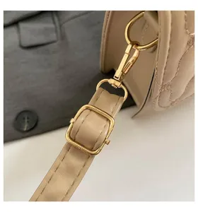 Vista detallada de la hebilla de metal dorado en bolso beige acolchado de calidad