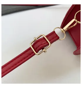 Detailansicht des roten Leder-Schultergurts mit goldener Metallschnalle an einer Handtasche