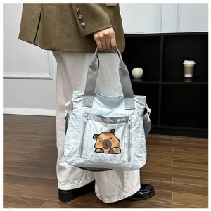 Detail view of light blue tote bag with cute capybara cartoon print and grey handles