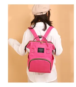 Vista trasera de una mochila para pañales multifuncional rosa vibrante usada por modelo