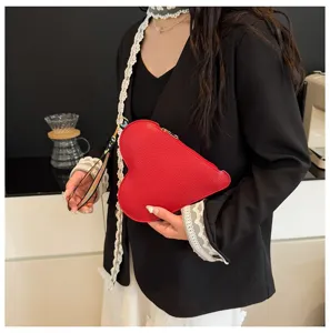 Vista detallada de una modelo sosteniendo un bolso de mano de cuero rojo con corazón.