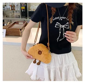 Cute Capybara plush croissant-shaped crossbody bag worn by a model in a cafe setting
