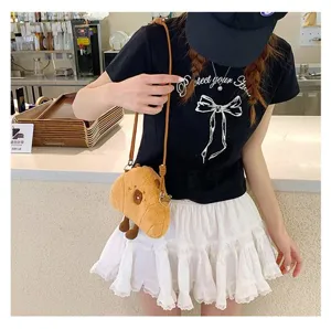 Detail view of a cute brown capybara plush crossbody bag worn by a model in a cafe setting