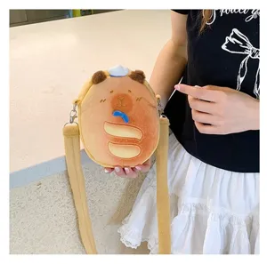 Close-up of a cute capybara plush crossbody bag held by a person in a white skirt.