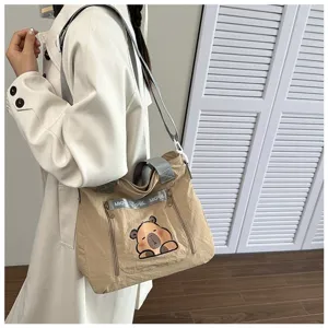 Detail view of a khaki canvas tote bag featuring a cute cartoon capybara print.