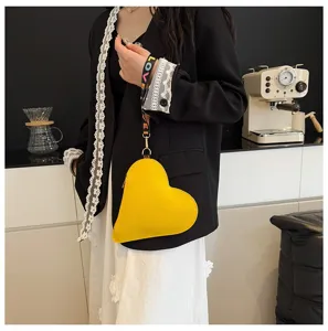 Elegante bolso bandolera amarillo con forma de corazón y correa colorida 'LOVE' en una modelo