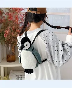 Detailansicht eines niedlichen Pinguin-Rucksacks aus Plüsch, getragen in gemütlichem Ambiente