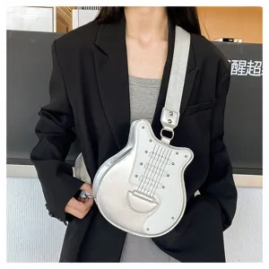 Silver guitar-shaped novelty crossbody bag with metallic finish worn over a black blazer.