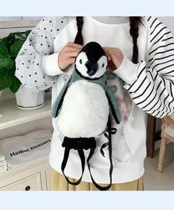 Modell trägt einen niedlichen Plüsch-Pinguin-Rucksack in einer Lifestyle-Umgebung