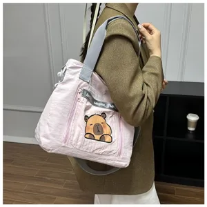 Model carrying a pink canvas shoulder bag with a cute Capybara cartoon print.