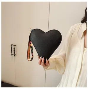 Primer plano de un bolso de mano negro con forma de corazón y correa LOVE