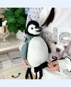 Nahaufnahme eines süßen Pinguin-Plüschrucksacks, gehalten von einem Model in Innenraum