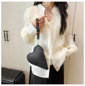 Detalle de monedero de cuero negro con forma de corazón y correa con estampado LOVE