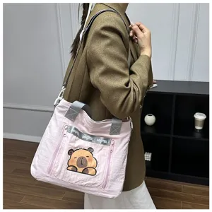Pink cartoon capybara print tote bag carried by a model in a stylish indoor room.