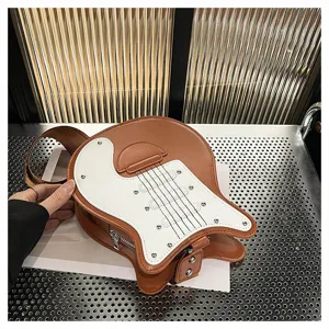 Detailed view of a creative guitar-shaped brown leather crossbody bag on a metal surface.