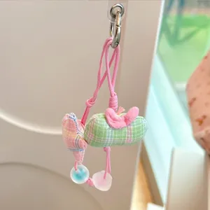 Close-up detail of a cute pink and green plaid rabbit pendant for iPhone case accessory.