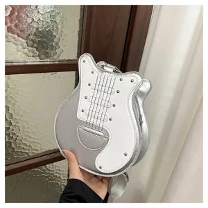 Creative guitar-shaped crossbody bag in silver and white with rivet details, held by hand