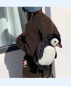 Rückansicht eines süßen Plüsch-Rucksacks in Pinguinform auf einem braunen Strickcardigan