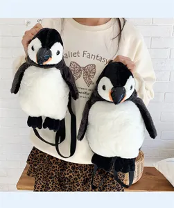Detailansicht von zwei Größen süßer Pinguin-Plüschrucksäcke, von einem Model getragen.