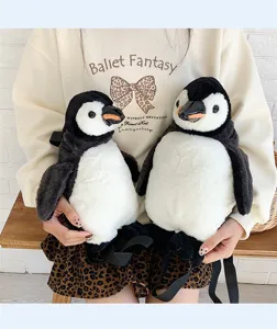 Nahaufnahme von zwei süßen Plüsch-Pinguin-Rucksäcken, von einer Schülerin gehalten