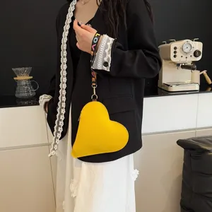 Bolso bandolera amarillo con forma de corazón y correa bordada 'LOVE' de colores.