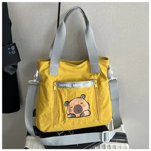 Detailed view of yellow nylon tote bag featuring cute cartoon capybara and grey straps