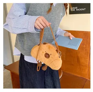 Detailed view of a cute brown capybara plush crossbody bag being held in a cozy setting