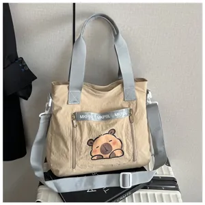 Cute beige canvas tote bag featuring a cartoon capybara print and grey adjustable shoulder strap