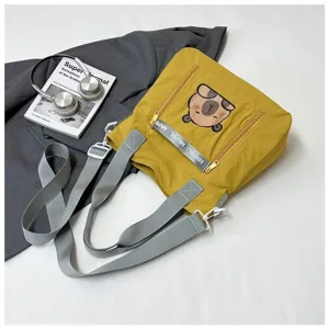 Close-up of a yellow canvas tote bag featuring a cute capybara print and grey handles.