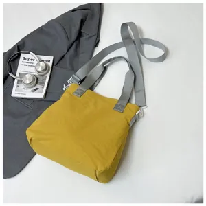 Lifestyle shot of a minimalist yellow large-capacity shoulder bag with grey straps and props